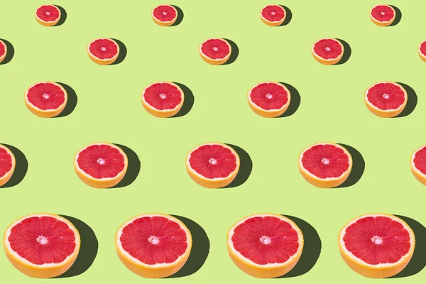 Flat lay fruit pattern of fresh grapefruit slices on green background. Minimal summer fruits pattern for blog or recipe book