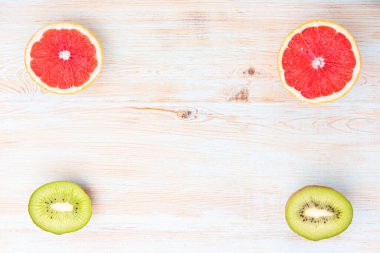 Minimum meyve arkaplanı. Mavi masada dilimlenmiş turunçgil, greyfurt ve kivi. Üst görünüm, düz, yat