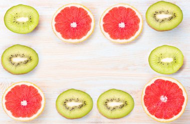 Minimum meyve arkaplanı. Mavi masada dilimlenmiş turunçgil, greyfurt ve kivi. Üst görünüm, düz, yat