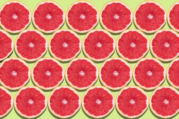Flat lay fruit pattern of fresh grapefruit slices on green background. Minimal summer fruits pattern for blog or recipe book