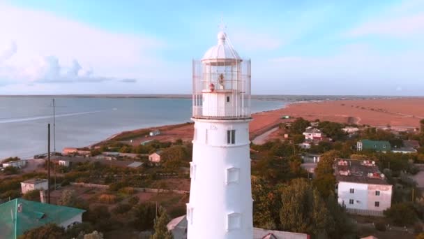 Drone zastřelil maják majáku na pláži při západu slunce. Maják na pozadí krásného západu slunce. — Stock video