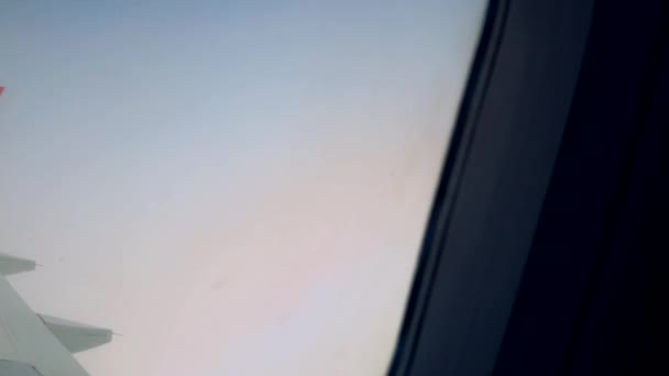 Vista del cielo blu e delle nuvole attraverso il finestrino dell'aereo, finestrino dell'aereo con ala dell'aereo, primo piano — Video Stock
