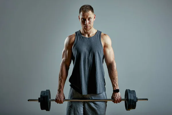 Hombre haciendo ejercicio de vuelta, fila de barras en el estudio sobre fondo gris. Copiar espacio —  Fotos de Stock