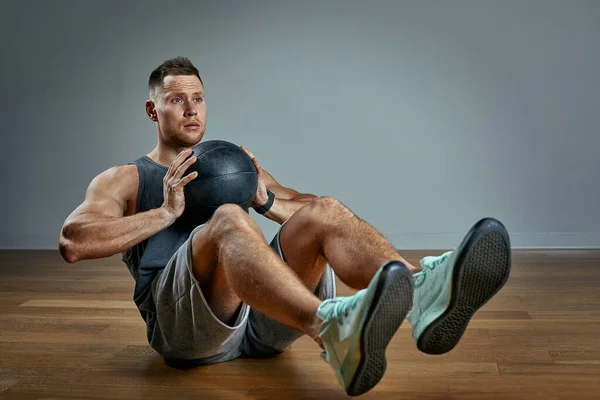 强壮的男人用医疗球做运动. 在灰色背景上,男人完美身材的照片. 力量和动机. — 图库照片
