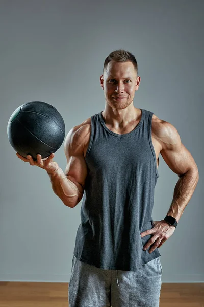 Silny człowiek ćwiczący z piłką medyczną. Zdjęcie człowieka doskonałej budowy ciała na szarym tle. Siła i motywacja. — Zdjęcie stockowe