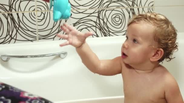 Le gamin se baigne dans la salle de bain avec sa mère et joue avec des jouets. Un bébé aux yeux bleus aux cheveux blonds se baigne de jouets sous la supervision de sa mère. Lavage et baignade des enfants, Hygiène et — Video