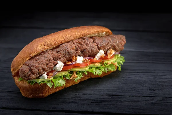 close up of kebab sandwich on black wooden background