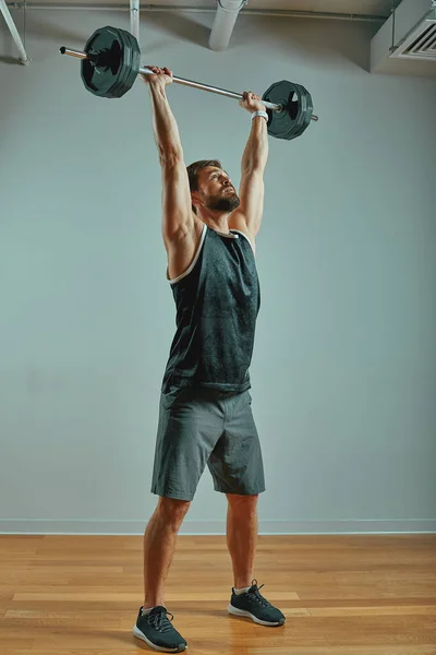 超级健康肌肉发达的年轻人在健身房锻炼的画像，带有灰色背景的杠铃，复制空间. — 图库照片
