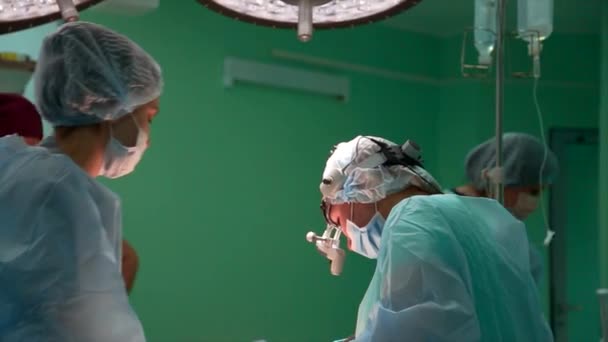 De chirurg en chirurgische team voeren cosmetische chirurgie aan de borsten in een ziekenhuis operatiekamer. De borstvergroting. Het werk van professor geneeskunde. Borstimplantaten. — Stockvideo