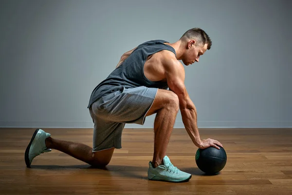 强壮的男人用医疗球做运动. 在灰色背景上,男人完美身材的照片. 力量和动机. — 图库照片