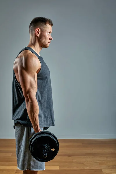 Hombre haciendo ejercicio de vuelta, fila de barras en el estudio sobre fondo gris. Copiar espacio —  Fotos de Stock