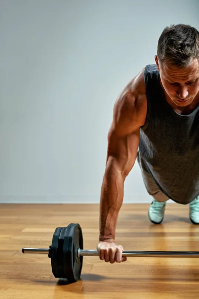 Man die weer aan het trainen is, lange rij in de studio over grijze achtergrond. Kopieerruimte — Stockfoto