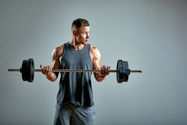 Man gör back workout, skivstång i studio över grå bakgrund. Kopiera utrymme — Stockfoto