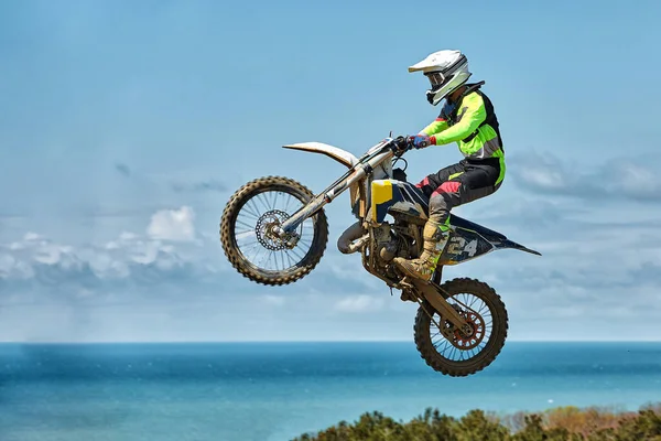 Deportes extremos, salto en moto. Motociclista hace un salto extremo contra el cielo. Efecto de grano de película, iluminación — Foto de Stock