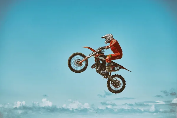Deportes extremos, salto en moto. Motociclista hace un salto extremo contra el cielo. Efecto de grano de película, iluminación — Foto de Stock