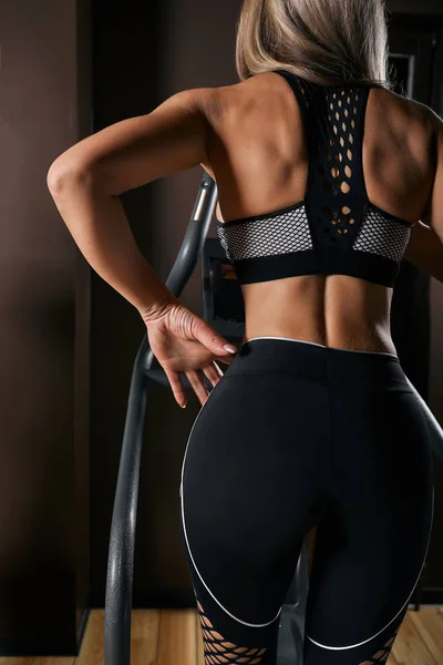 Sportowa kobieta jazda ćwiczenie krok symulator podczas treningu rowerowego w siłowni. Widok z tyłu — Zdjęcie stockowe