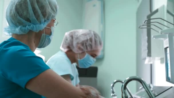 Médicos cirujano en bata se lava las manos en el lavabo antes de la cirugía — Vídeo de stock