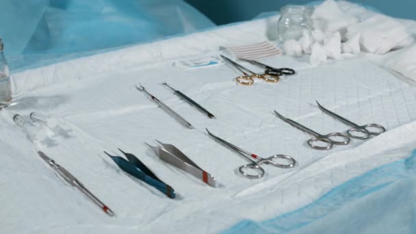 Ιατρική ιδέα, χειρουργική επέμβαση. Χειρουργικό τραπέζι με ένα εργαλείο για χειρουργική επέμβαση, κοντινό, μπλε φως. Στο τραπέζι απλώνονται τα Στέρνι όργανα των χειρουργών, νυστέρια, κλιπ, ταμπόν, σύριγγες. — Αρχείο Βίντεο