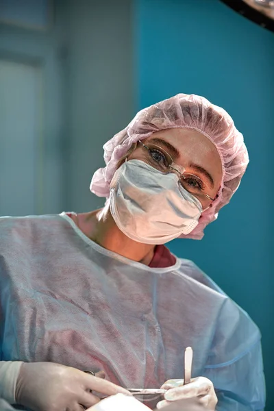 Крупним планом портрет молодої жінки-хірурга, який носить захисну маску та капелюх під час операції. Охорона здоров'я, медична освіта, концепція хірургії — стокове фото