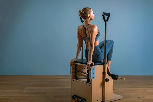 Pilates vrouw in een hervormer doet stretching oefeningen in de sportschool. Fitness concept, speciale fitnessapparatuur, gezonde levensstijl, plastic. Kopieerruimte, sportbanner voor reclame — Stockfoto