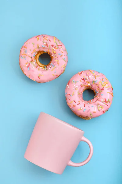 Donuts roses avec glaçage et café cu pon fond bleu pastel. Doux beignets . — Photo