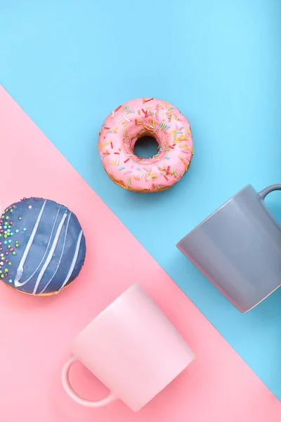 Пончики с глазурью и чашки кофе на пастельно-голубом и розовом фоне. Сладкие пончики . — стоковое фото
