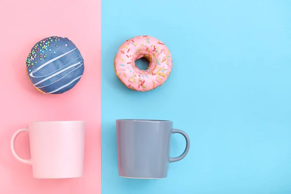Donuts mit Zuckerguss und Kaffeetassen auf pastellblauem und rosa Hintergrund. süße Donuts. — Stockfoto