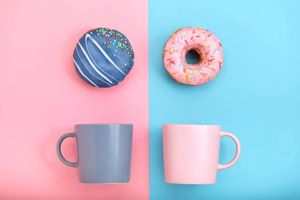 Donuts mit Zuckerguss und Kaffeetassen auf pastellblauem und rosa Hintergrund. süße Donuts. — Stockfoto