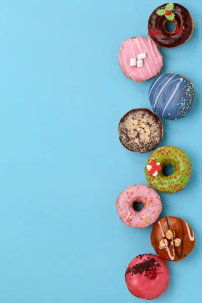 Top view of assorted donuts on blue background with copy space. Colorful donuts background. Various glazed doughnuts with sprinkles. — 스톡 사진