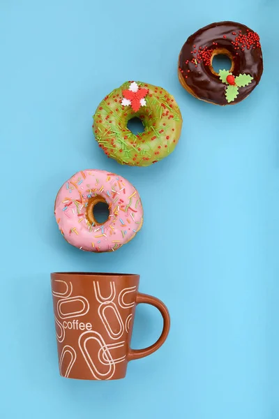 Donuts coloridos com gelo e xícara de café no fundo azul pastel. Doce donuts . — Fotografia de Stock