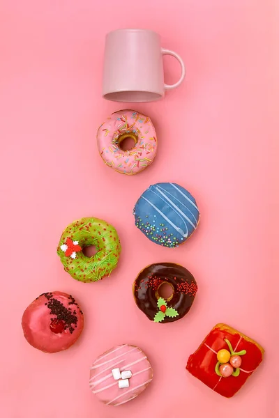 Ciambelle colorate con glassa e tazze di caffè su sfondo rosa pastello. Ciambelle dolci . — Foto Stock