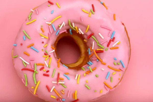 Pink donut with colored sprinkles on a pink background, close-up, concept of desserts, concept of pink color on pink. — Stock Photo, Image