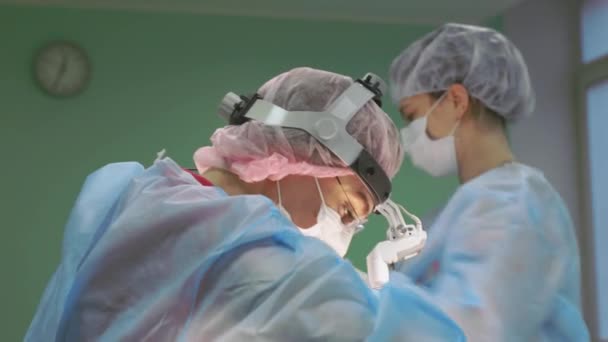 Surgical team during the operation. Surgeons work as a friendly team, professionals in the blue modern operating room. Teamwork, real operation, blue light. Plastic surgery, close-up, health. — Stock Video