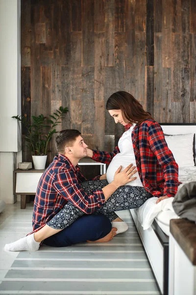 Yatak odasında güzel hamile bir çift var. Doğum hazırlıkları, mutlu ebeveynler, ilk çocuğu beklemek. Doğumdan önce kadınlara destek. — Stok fotoğraf