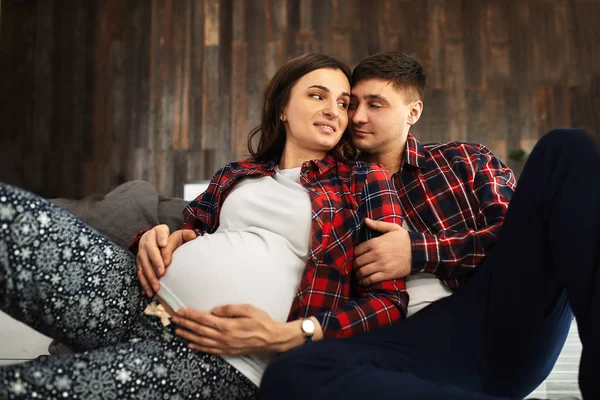 Yatak odasında güzel hamile bir çift var. Doğum hazırlıkları, mutlu ebeveynler, ilk çocuğu beklemek. Doğumdan önce kadınlara destek. — Stok fotoğraf