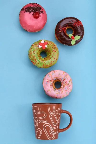 A mug from which sweet donuts fly out, on a blue background. Sweet and coffee donuts concept. color on blue. Mock up for design. Copy space.