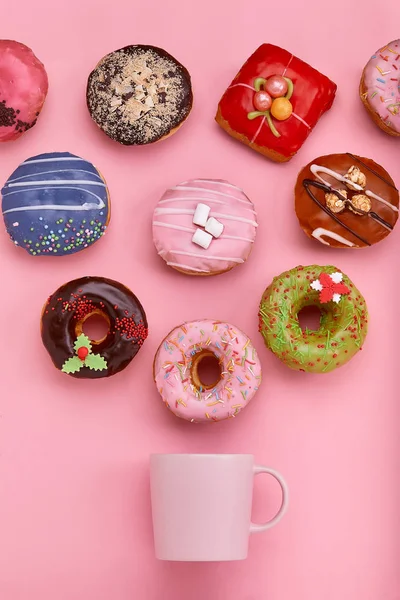 Кружка, из которой вылетают сладкие пончики, на розовом фоне. Концепция сладких и кофе пончиков. цветной на розовом. Макет для дизайна. Копирование пространства . — стоковое фото