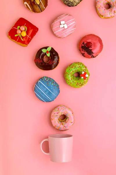 एक मग जिसमें से मीठे डोनट गुलाबी पृष्ठभूमि पर बाहर उड़ते हैं। मीठे और कॉफी डोनट अवधारणा। गुलाबी पर रंगीन। डिजाइन के लिए नकली। स्थान नक़ल करें . — स्टॉक फ़ोटो, इमेज