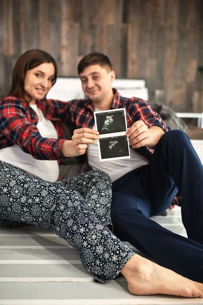 Mutlu ve heyecanlı hamile Çift yatakta yatıyordu onların bebek ultrason görüntülerini bakarak — Stok fotoğraf