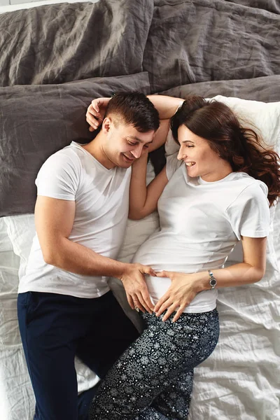 Hermosa pareja embarazada en el dormitorio. Preparándose para el parto, padres felices, esperando al primer hijo. Apoyo a las mujeres antes del parto . — Foto de Stock