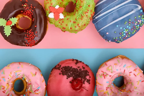 Сладкие пончики на голубом и розовом фоне. Ассорти пончиков, пограничный цвет синий розовый фон . — стоковое фото