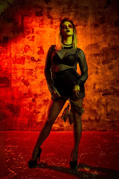 Modèle féminin en tenue d'Halloween posant sur un fond rouge. Magnifique fille en vêtements célèbre le jour des morts. Concept d'Halloween, costume de sorcière, couleurs vives, punk vapeur . — Photo
