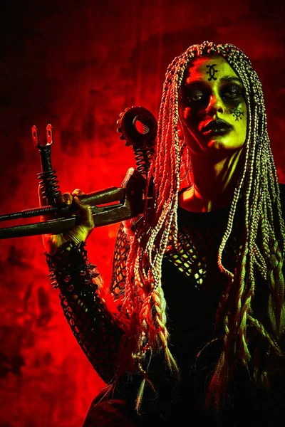 Modèle féminin en tenue d'Halloween posant sur un fond rouge. Magnifique fille en vêtements célèbre le jour des morts. Concept d'Halloween, costume de sorcière, couleurs vives, punk vapeur . — Photo