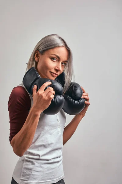 Jovem bela mulher sexy boxer posando com luvas de boxe preto em suas mãos em um fundo cinza. Espaço de cópia, fundo cinza, realização objetivo . — Fotografia de Stock