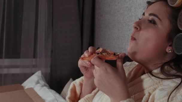 Товста дівчина їсть піцу в ліжку. Ожиріння, проблеми сучасного харчування, фаст-фуд, дієта, їжа вночі. Проблеми з надмірною вагою . — стокове відео