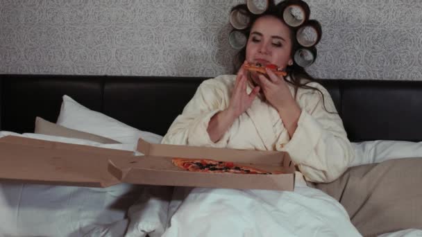 Gadis gemuk makan pizza di tempat tidur. Kegemukan, masalah nutrisi modern, makanan cepat saji, diet, makan di malam hari. Masalah kelebihan berat badan . — Stok Video