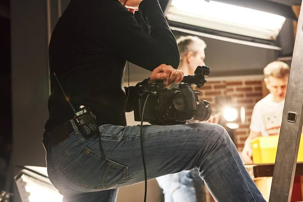 Video production backstage. Behind the scenes of creating video content, a professional team of cameramen with a director filming commercial ads. Video content creation, video creation industry.