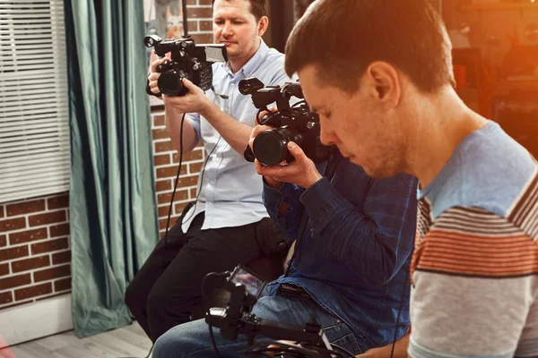 Video production backstage. Behind the scenes of creating video content, a professional team of cameramen with a director filming commercial ads. Video content creation, video creation industry. — Stock Photo, Image