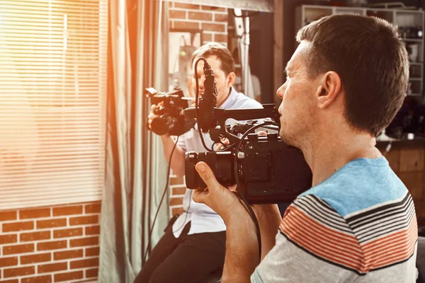 Video production backstage. Behind the scenes of creating video content, a professional team of cameramen with a director filming commercial ads. Video content creation, video creation industry. — Stock Photo, Image