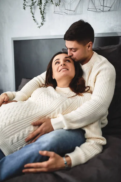 Amar a la pareja embarazada, acostarse en la cama y mirarse. En previsión del bebé, una nueva vida, la felicidad y los problemas de una familia joven en el nacimiento de un niño . — Foto de Stock